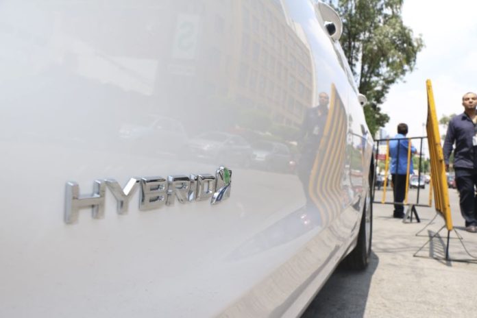 A close up view of a white hybrid car with the word hybrid on the passenger's side door