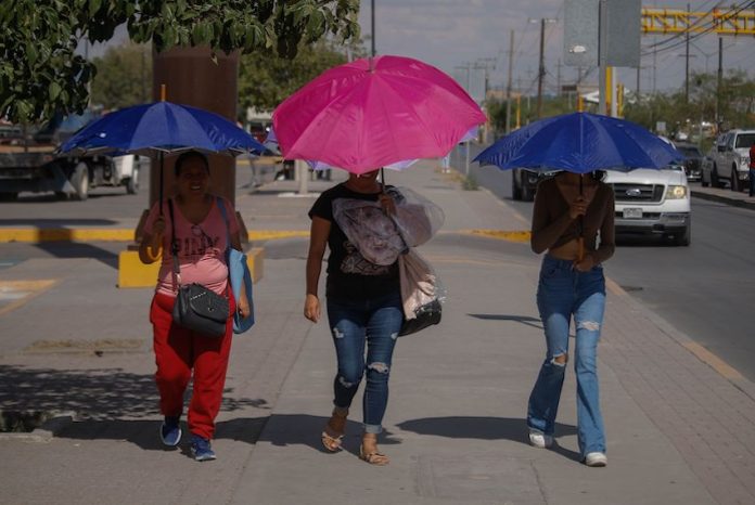 Three women shield themselves with umbrellas during a heat wave in Mexico.