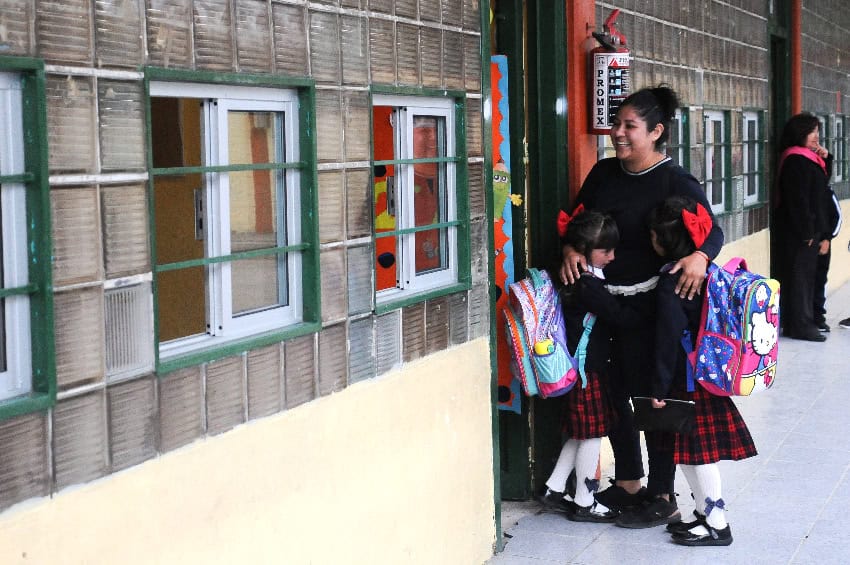 A mother with her two daughters outside a school classroom