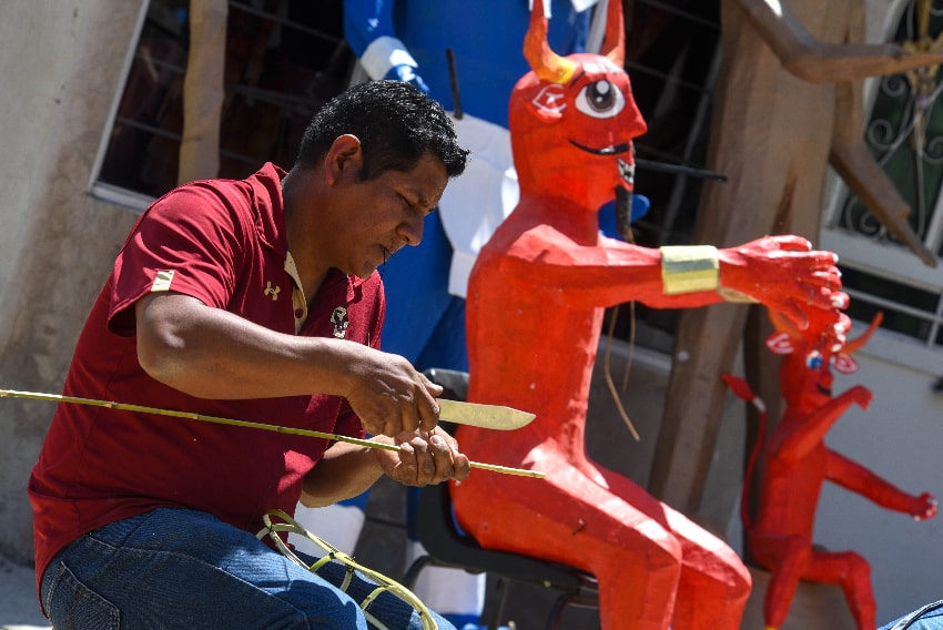 An artisan works on a wooden figure of Judas