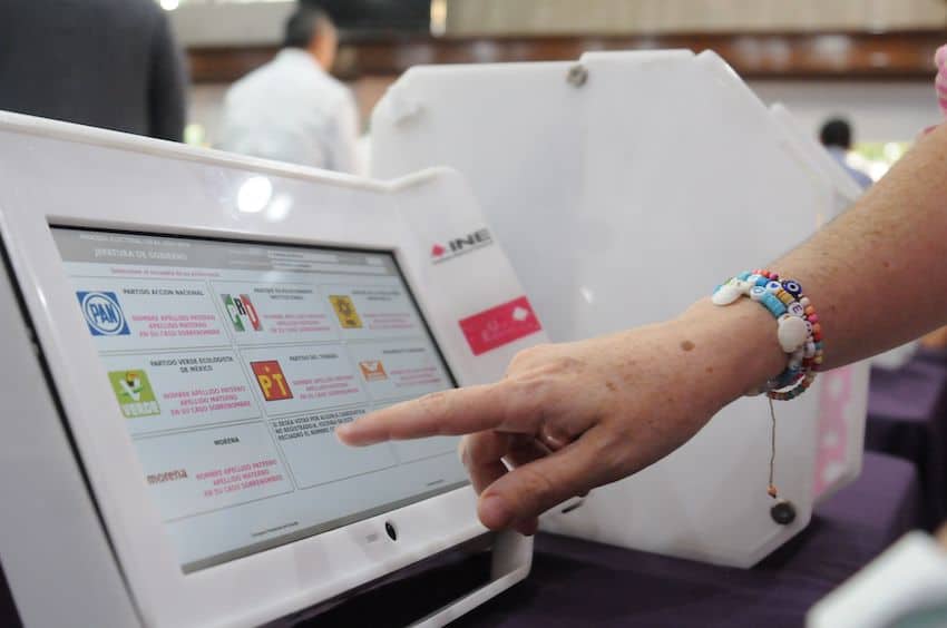 A Mexican citizen presses a button on an official voting machine.