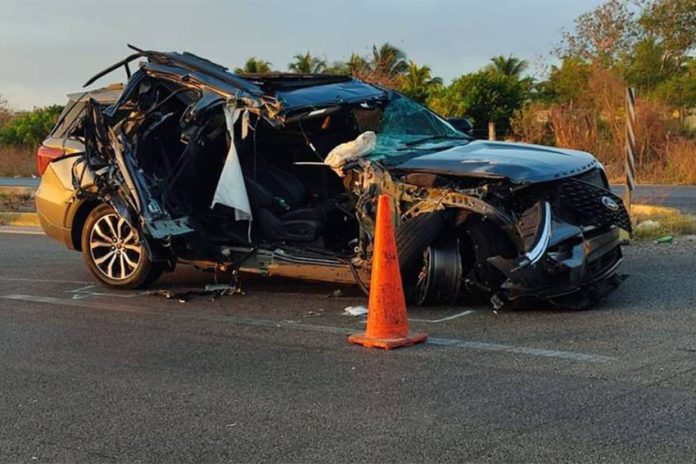 A mangled Ford SUV on a highway parked next to an orange highway cone