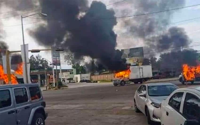 Burning vehicles scattered across a large road