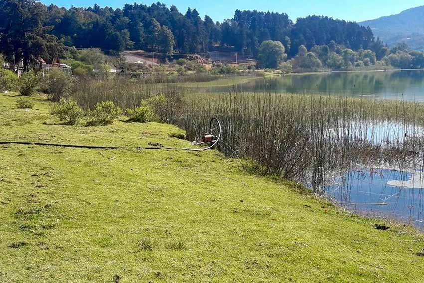 Michoacan's Zirahuen lake with a pump and hose sitting on the lake's shore.