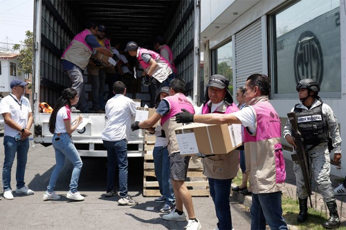 INE workers in Puebla unload ballot boxes for the Mexican elections, while soldiers and official observers watch.