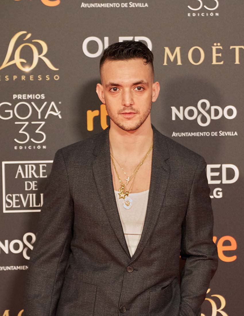 Rapper C. Tangana, who will attend the Guadalajara film festival, posing in front of a red carpet wall filled with logos for various sponsor brands at the 2019 Premios Goya