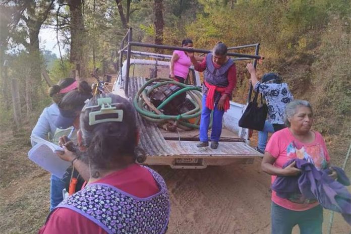 Elderly women carrying pumps and hoses into a pickup truck in rural Michoacan