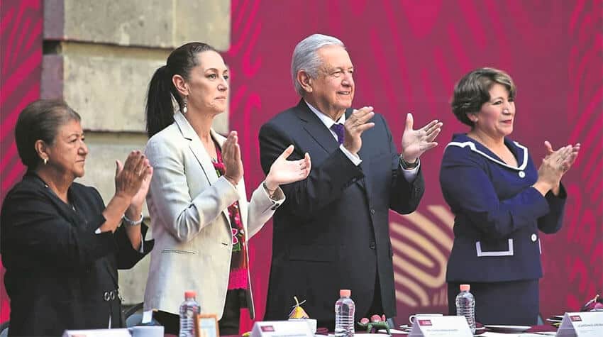 Claudia Sheinbaum and President López Obrador stand next to each other clapping at an event.
